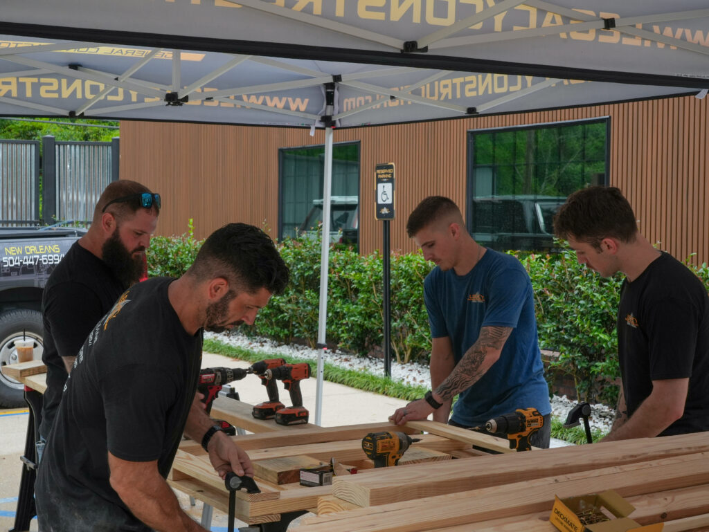 Impact Day 2026: Building More Than Beds 9 Legacy Construction team members drilling and assembling wooden bed frames for children survivors of human trafficking at Legacy Day 2026