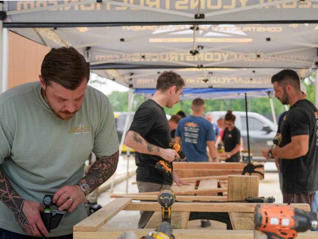 Impact Day 2026: Building More Than Beds 10 Legacy Construction employees and community volunteers finishing wooden bed frames at Legacy Day 2026