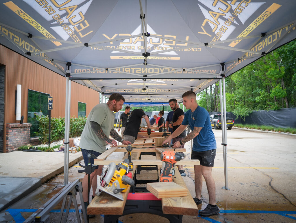 Impact Day 2026: Building More Than Beds 4 Legacy Construction and Development team actively building wooden bed frames during Legacy Day 2026 community service event