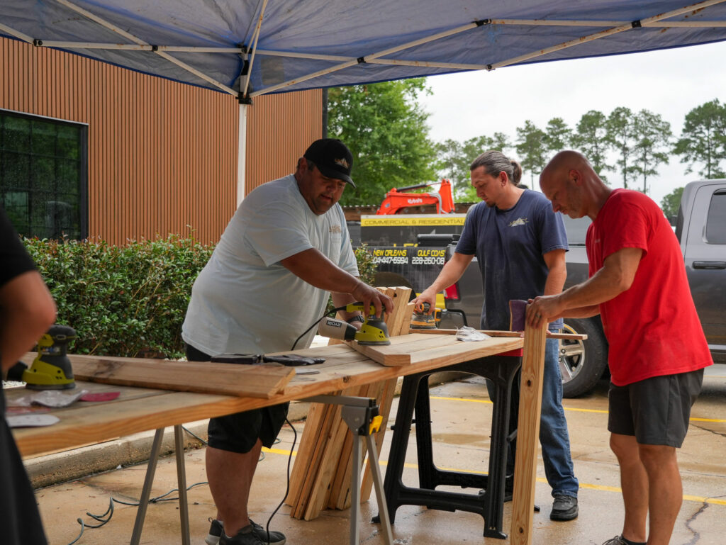 Impact Day 2026: Building More Than Beds 6 Legacy Construction crew working together on wooden bed frames at Legacy Day 2026, a volunteer build supporting children survivors of human trafficking