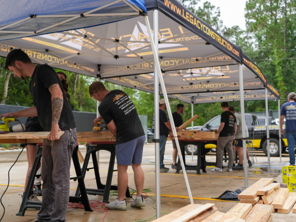 Impact Day 2026: Building More Than Beds 7 Legacy Construction employees using power tools to construct bed frames during Legacy Day 2026 community giveback event