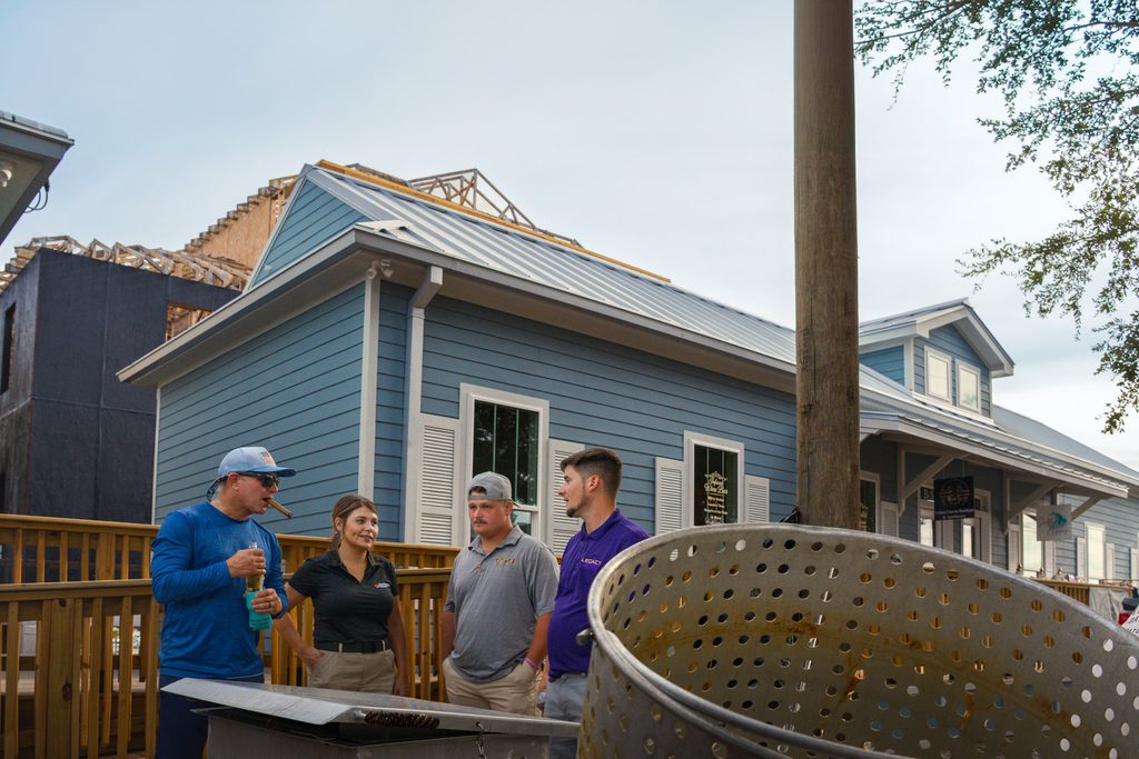 Four guests talk beside the outdoor cooking station, with a large boiling basket in the foreground at Eagan’s topping-out party.