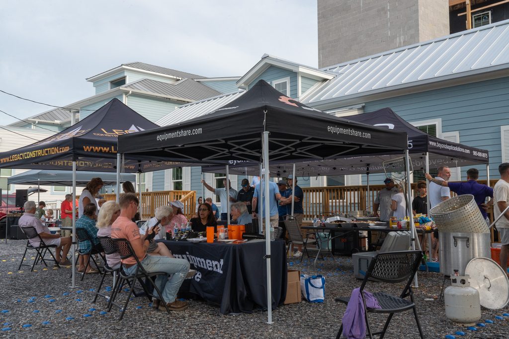 Guests dine beneath Legacy and EquipmentShare tents beside serving tables and cooking equipment at Eagan’s topping-out party.